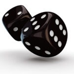 Two black dice with white dots tumbling through the air, casting a shadow on a white surface.