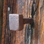 Rustic square nail embedded in textured wood, showcasing vintage carpentry craftsmanship and weathered charm.