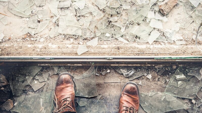 man standing beside broken glass