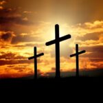 Three crosses silhouetted against a dramatic sunset sky, symbolizing faith and hope.