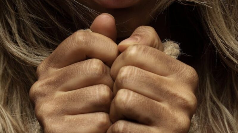 Close-up of hands clenching around a rope, suggesting strength and resilience.