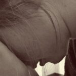 Person with head in hands, appearing stressed or upset, looking downward.