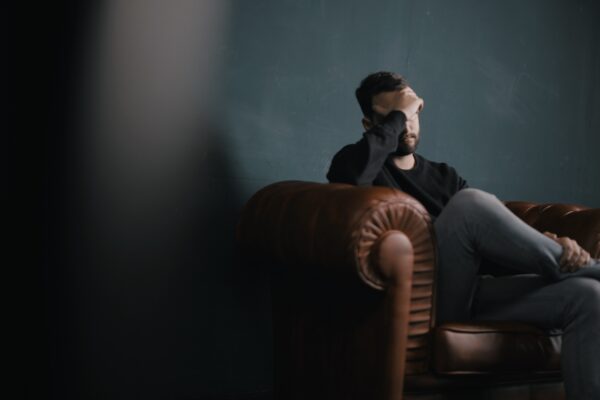 man on chair with hand over face