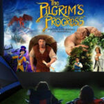 Outdoor movie night featuring The Pilgrim's Progress with tents and audience at dusk.