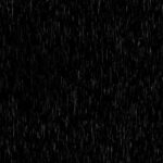 Heavy rainfall at night, with streaks of rain against a dark background.