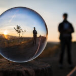 Silhouette reflected in a glass sphere with sunset background, creating a creative and artistic optical illusion.