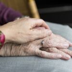 Elderly hands showing support, one gently resting on the other, symbolizing care and companionship.