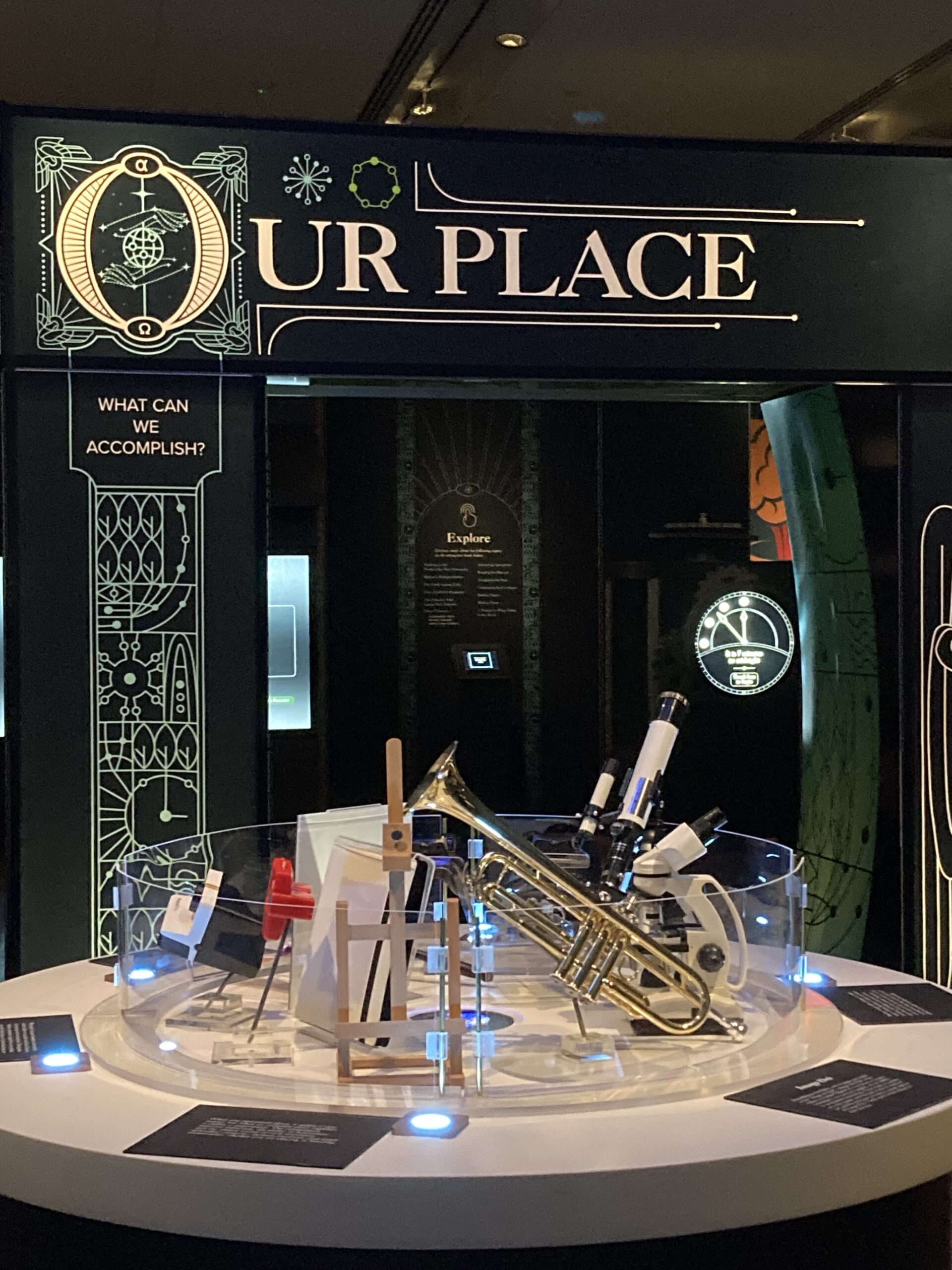 Interactive exhibit with trumpet and telescopes at Our Place display, highlighting human accomplishments in science and art.