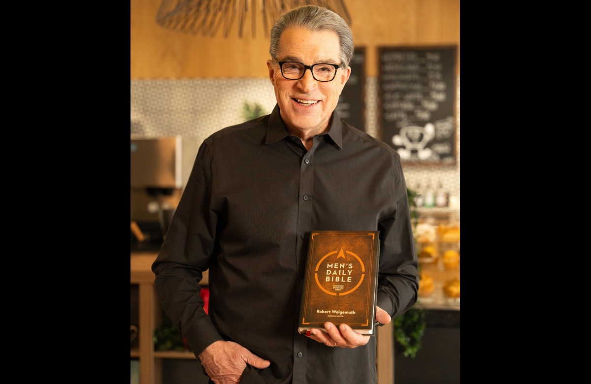 Man smiling, holding a copy of Men's Daily Bible in a cozy setting.