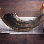 A Shofar Rams Horn and a Tora Scroll on a Wooden Table