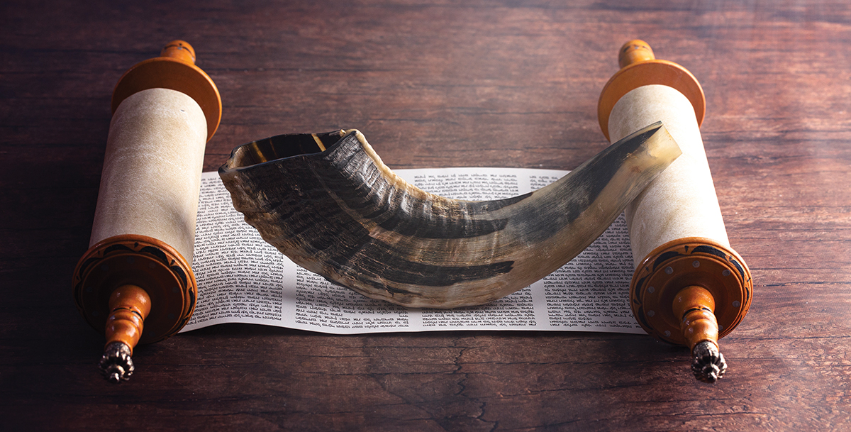 A Shofar Rams Horn and a Tora Scroll on a Wooden Table