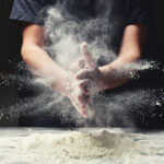 Clap hands of baker with flour in kitchen