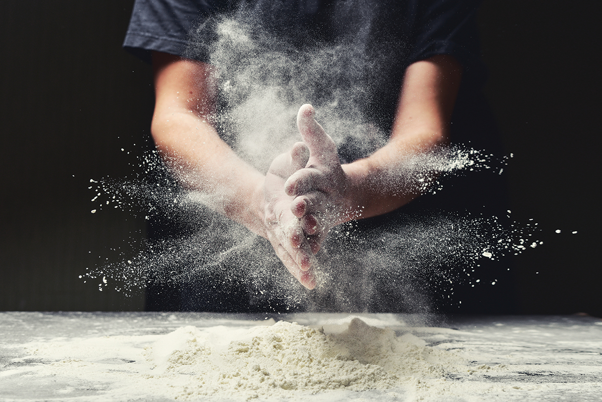 Clap hands of baker with flour in kitchen