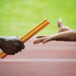 Two men passing golden baton in stadium