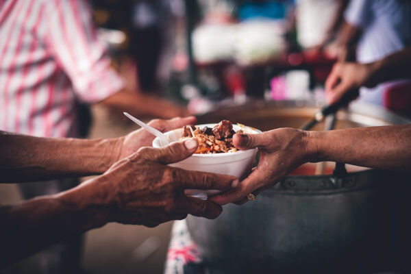 Concept of giving free food to the poor in the community : Volunteers handing out food to hungry people